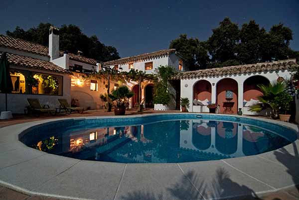 A large, mission-style home with an elegan bean-shaped pool